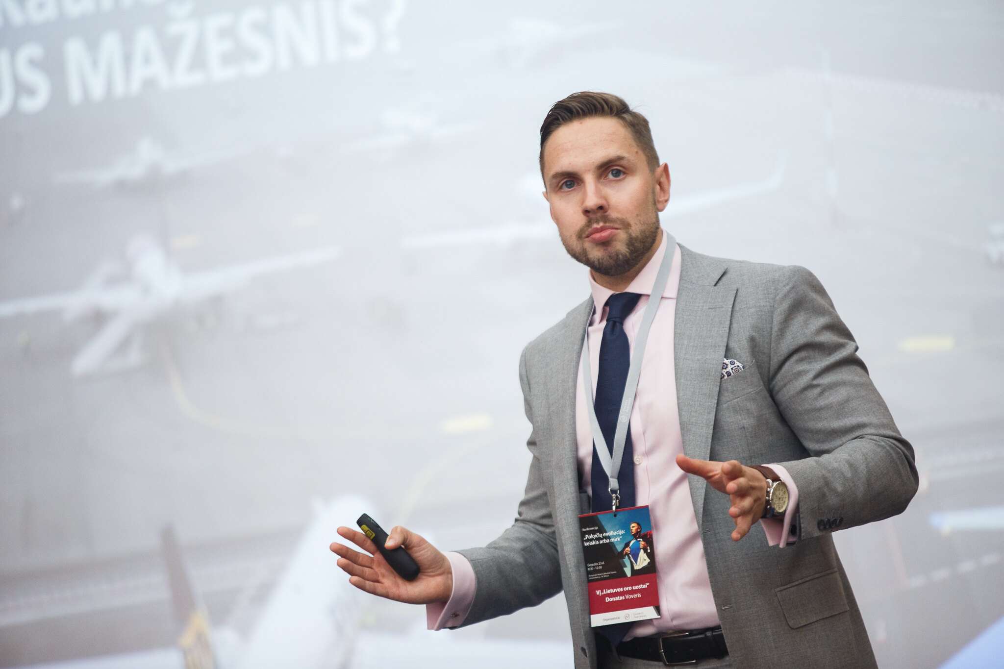 Konferencijos pranešėjas su dalyvio kortele scenoje
