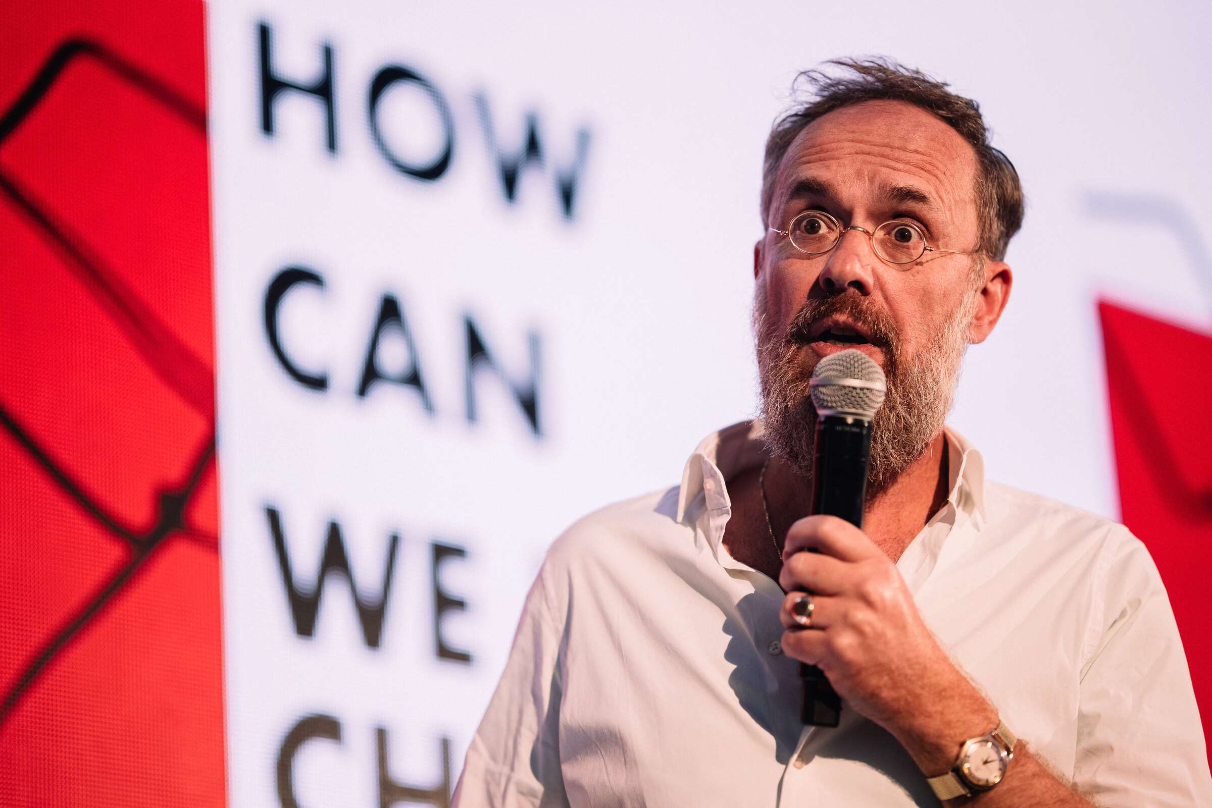 Pranešėjas kalba scenoje ryškios skaidrės fone
