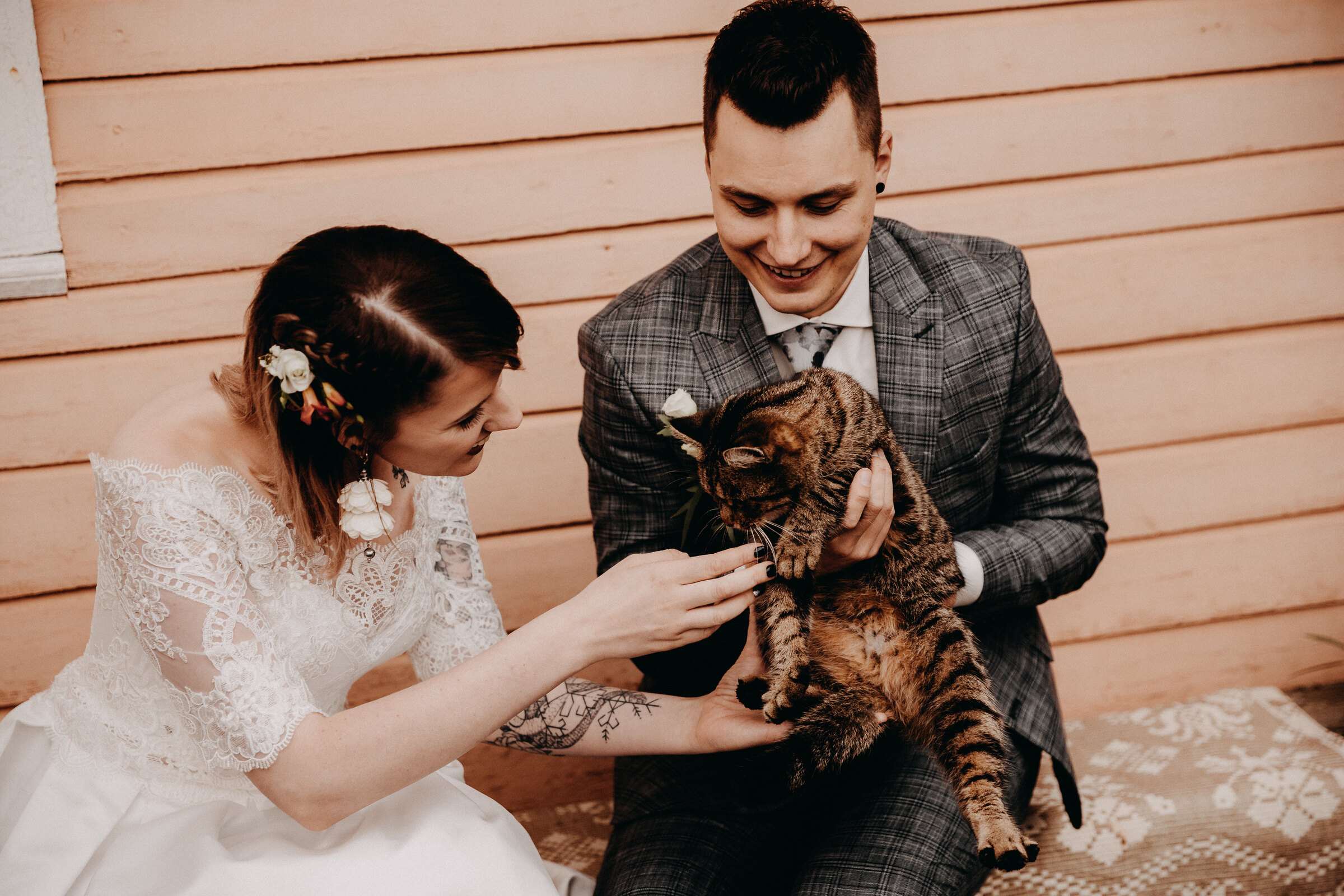 Jaunieji juokdamiesi glosto rainą katiną ant medinės verandos