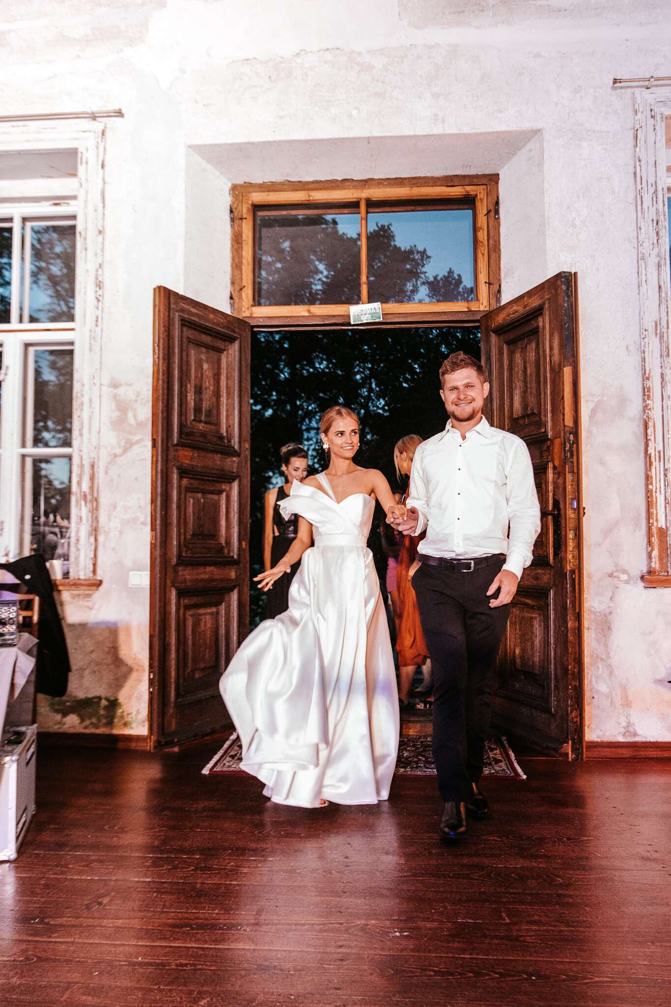 Jaunieji įeina pro aukštas medines senojo dvaro duris