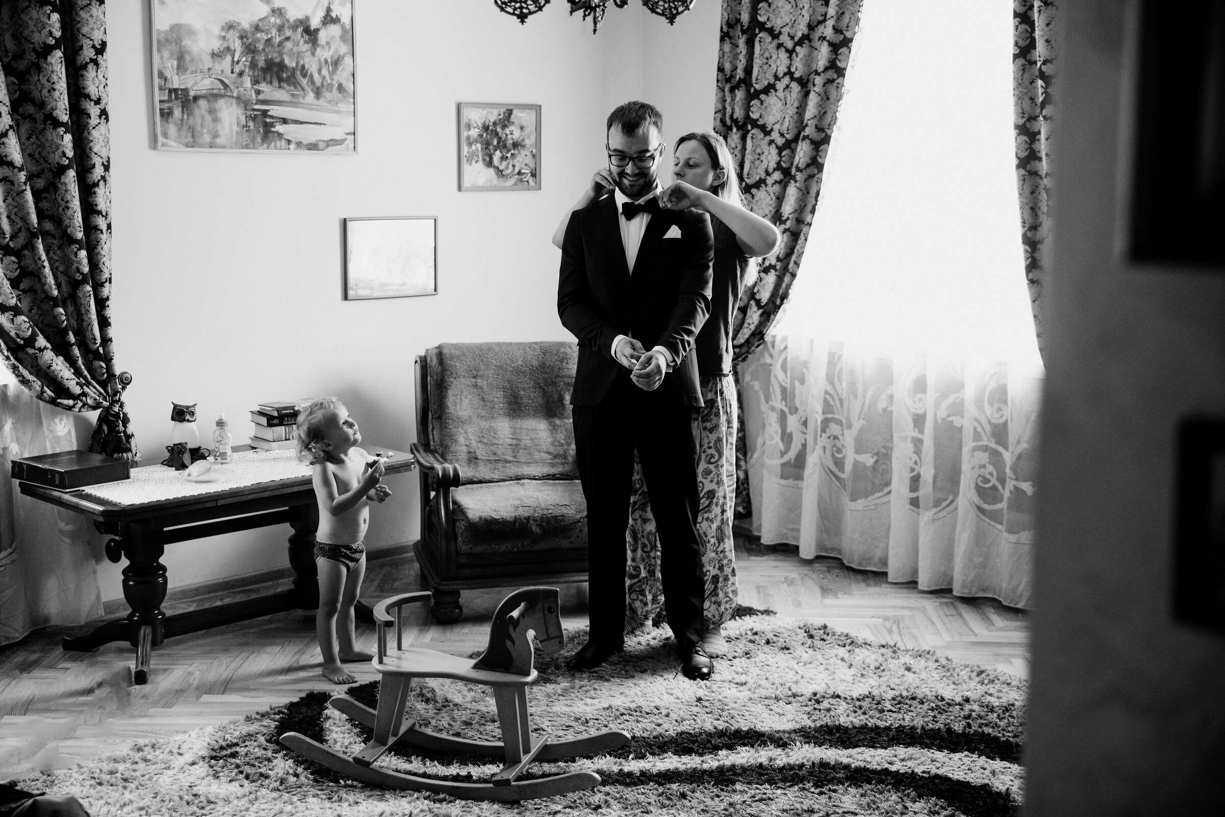 Jaunikis ruošiasi, šalia žaidžia mažylis, nespalvota